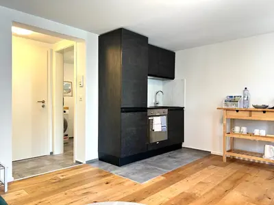 a kitchen with black cabinets and wooden floors at Klara 1011 - Olma, Spital, Uni St- Gallen in St. Gallen