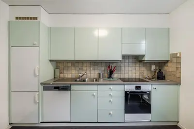 a white kitchen with white cabinets and a sink at Zimmer mit Gemeinschaftsbad in Arbon