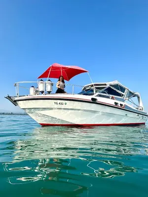 a white boat with a red umbrella on the water at Gemütliches Motorboot im Yachthafen von Romanshorn in Romanshorn