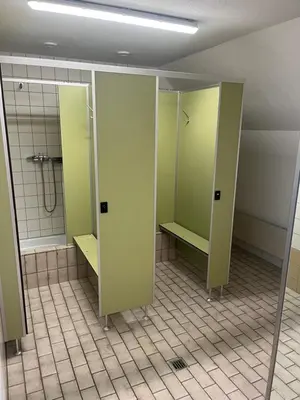a bathroom with green stalls and a shower at Mattenhof in Flawil