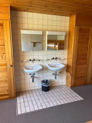 a bathroom with three sinks and two mirrors at Mattenhof in Flawil