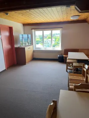 an empty classroom with tables and chairs and a window at Mattenhof in Flawil