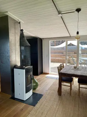 a living room with a table and a stove at Charmante Bungalows mit Traumaussicht in Wienacht-Tobel