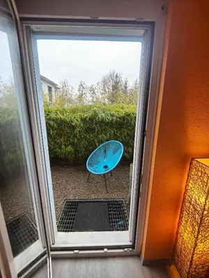 a sliding glass door with a blue table outside at Zimmer oberhalb einer Schokoladenfabrik in Kreuzlingen