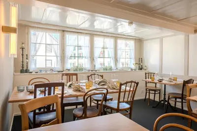 a dining room with tables and chairs and windows at Gasthaus zur Sonne - Hotel - Restaurant - Boutique in Gossau