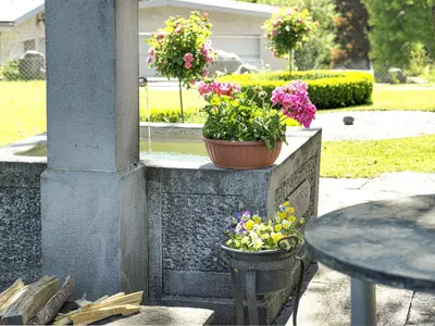two potted flowers on a stone pillar with a table at Hotel B&BAlpenheim in Teufen