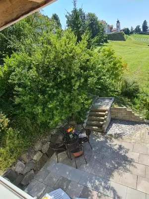 a patio with a table and chairs under a tree at Maisonette-Wohnung inmitten der Natur in Wald