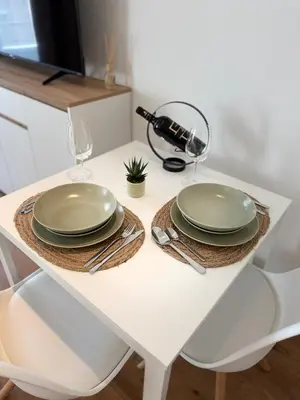 a white table with two plates and glasses on it at Studio mit Balkon im Zentrum in St. Gallen