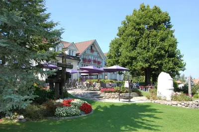 a building with purple umbrellas and flowers in a yard at Hotel und Restaurant Wolfensberg in Degersheim