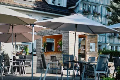 an outdoor cafe with tables and chairs and umbrellas at Hotel und Restaurant Wolfensberg in Degersheim