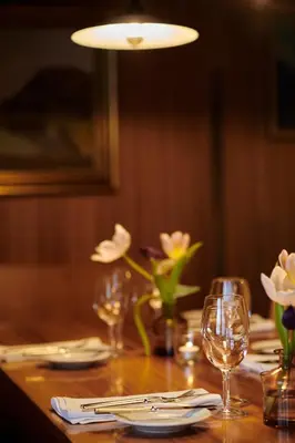 a wooden table with glasses and flowers on it at Hotel und Restaurant Wolfensberg in Degersheim
