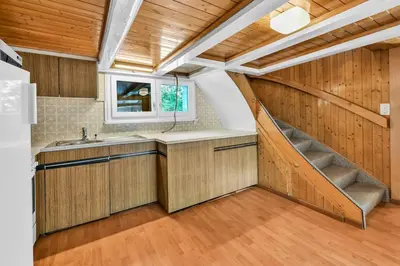 an attic kitchen with a staircase and a sink at romatisches Chalet mit Bodenseesicht in Wolfhalden