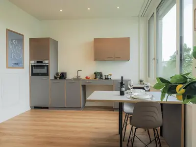 a kitchen with stainless steel appliances and a table with chairs at Stilvoll&zentral in St Gallen -WYBA Living P in St. Gallen