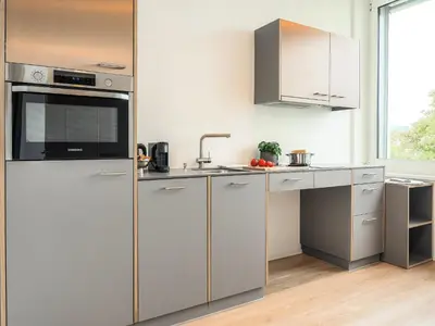 a kitchen with stainless steel appliances and white cabinets at Stilvoll&zentral in St Gallen -WYBA Living P in St. Gallen