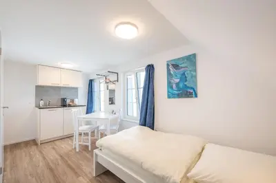 a bedroom with a bed and a table and a kitchen at CasaMia Flawil in Flawil