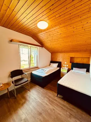 two beds in a room with a wooden ceiling at Dreibettzimmer mit eigenem Bad und Seeblick in Heiden