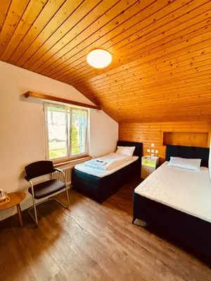two beds in a room with a wooden ceiling at Dreibettzimmer mit eigenem Bad und Seeblick in Heiden