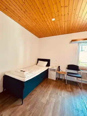 a bedroom with a bed and a desk and a chair at Dreibettzimmer mit eigenem Bad und Seeblick in Heiden