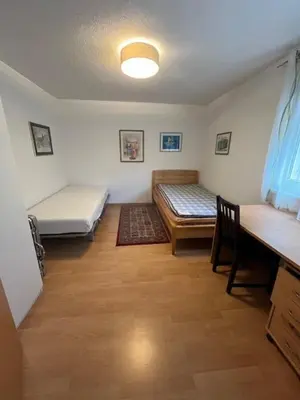 a room with two beds and a desk and a table at Holiday home with pool & dream view over Lake Constance in Rorschacherberg