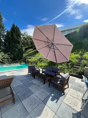 a patio with two chairs and a pink umbrella at Holiday home with pool & dream view over Lake Constance in Rorschacherberg