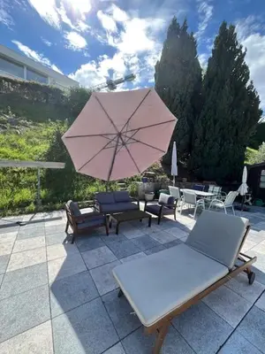 a patio with chairs and a pink umbrella at Holiday home with pool & dream view over Lake Constance in Rorschacherberg