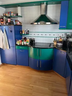 a kitchen with blue and green cabinets and a wooden floor at Holiday home with pool & dream view over Lake Constance in Rorschacherberg