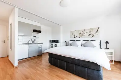 a white bedroom with a large bed and a kitchen at SOHO 4B !Gratis Parken, Free Parking! in Kreuzlingen