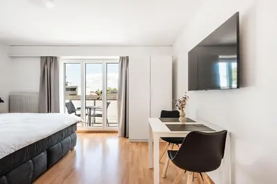a bedroom with a bed and a desk and a balcony at SOHO 4B !Gratis Parken, Free Parking! in Kreuzlingen