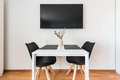 a white table with black chairs and a tv on a wall at SOHO 4B !Gratis Parken, Free Parking! in Kreuzlingen