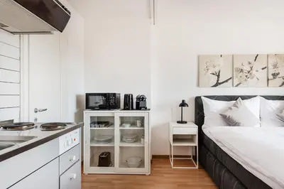 a white bedroom with a bed and a kitchen at SOHO 4B !Gratis Parken, Free Parking! in Kreuzlingen