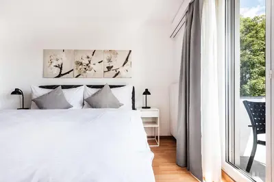a white bedroom with a bed and a window at SOHO 4B !Gratis Parken, Free Parking! in Kreuzlingen