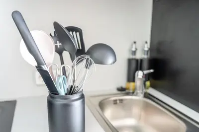 a container of utensils sitting next to a kitchen sink at Seesicht - Rückzugsort oberhalb vom Bodensee in Wienacht-Tobel
