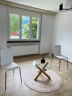 a living room with two chairs and a glass table at SwissRest - Self Check-In in Sevelen