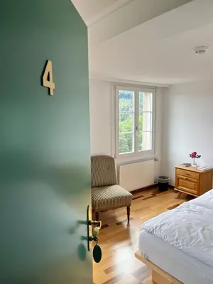 a bedroom with a bed and a chair and a window at Krone Trogen in Trogen