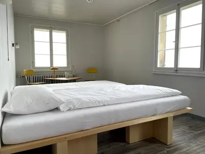 a bed in a room with a table and two windows at Krone Trogen in Trogen