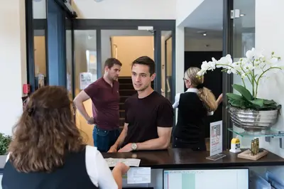 a group of people standing around a counter in an office at Hotel one66 (free parking garage) in St. Gallen