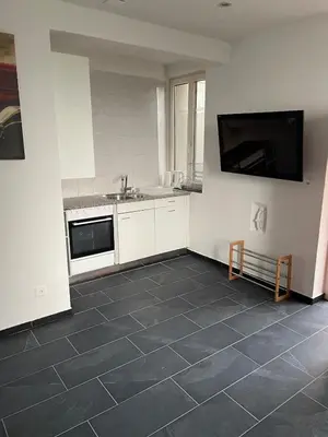 a kitchen with white cabinets and a tiled floor at 1-room studio apartment in St. Gallen