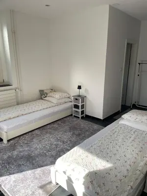 a room with two beds and a table with a lamp at 1-room studio apartment in St. Gallen