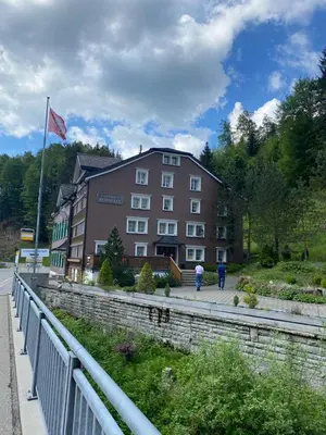 a building with a flag and people walking in front of it at Gästehaus Rossfall 424 - Self-Check-in in Urnäsch