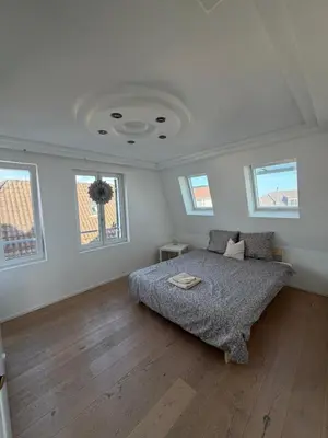 a bedroom with a bed in a room with windows at Elegante Maisonette mit See-Panorama in Rorschach in Rorschach
