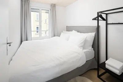 a white bed with white sheets and a window at BLIV Grosszügiges Altbaujuwel im Zentrum in St. Gallen