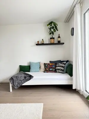 a white couch sitting in a room with a window at HRE Apartments Lago Rorschach in Rorschach