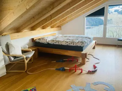 a bedroom with a bed and a chair in a attic at Ferienwohnung mit Sauna in Wildhaus in Wildhaus