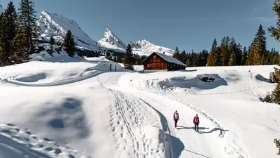 two people skiing in the snow in front of a cabin at Ferienwohnung mit Sauna in Wildhaus in Wildhaus