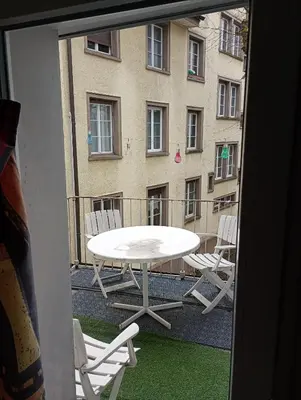 a table and chairs on a balcony with a building at Central tiny studio in St. Gallen
