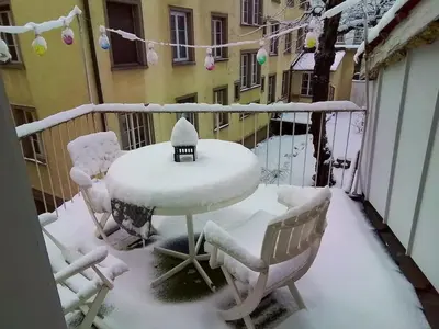 a table and chairs covered in snow on a balcony at Central tiny studio in St. Gallen