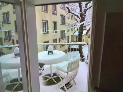 a balcony with a table and chairs covered in snow at Central tiny studio in St. Gallen