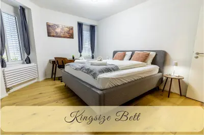 a bedroom with a bed and a table and windows at Jasminkas Host 3 - Stadtwohnung mit Küche & gratis Parkplatz in St. Gallen