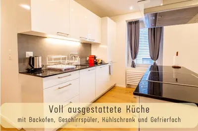a kitchen with white cabinets and black counter tops at Jasminkas Host 3 - Stadtwohnung mit Küche & gratis Parkplatz in St. Gallen