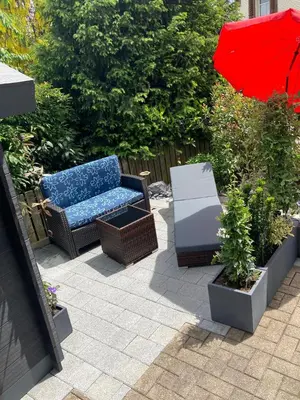 a patio with a couch and a red umbrella at Dachwohnung in Niederuzwil